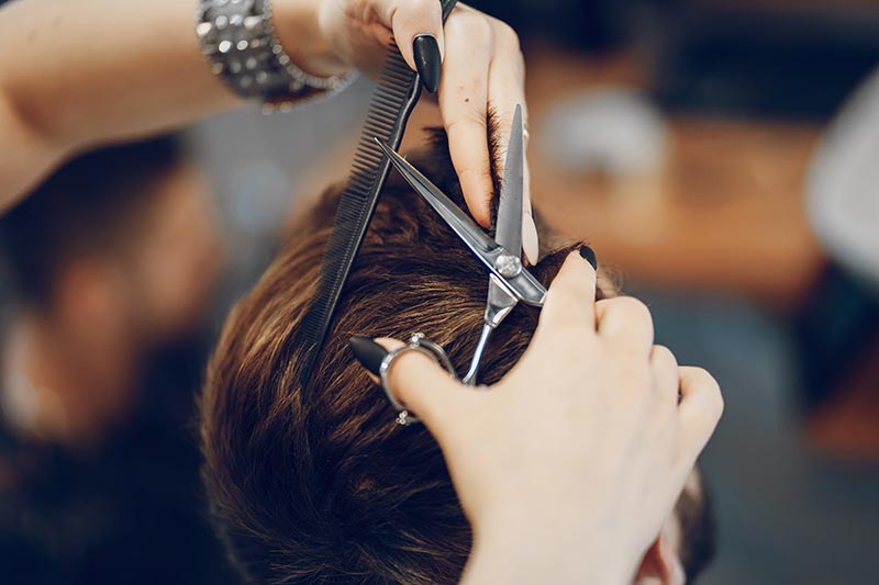 coiffeuse coupant les cheveux d'un homme